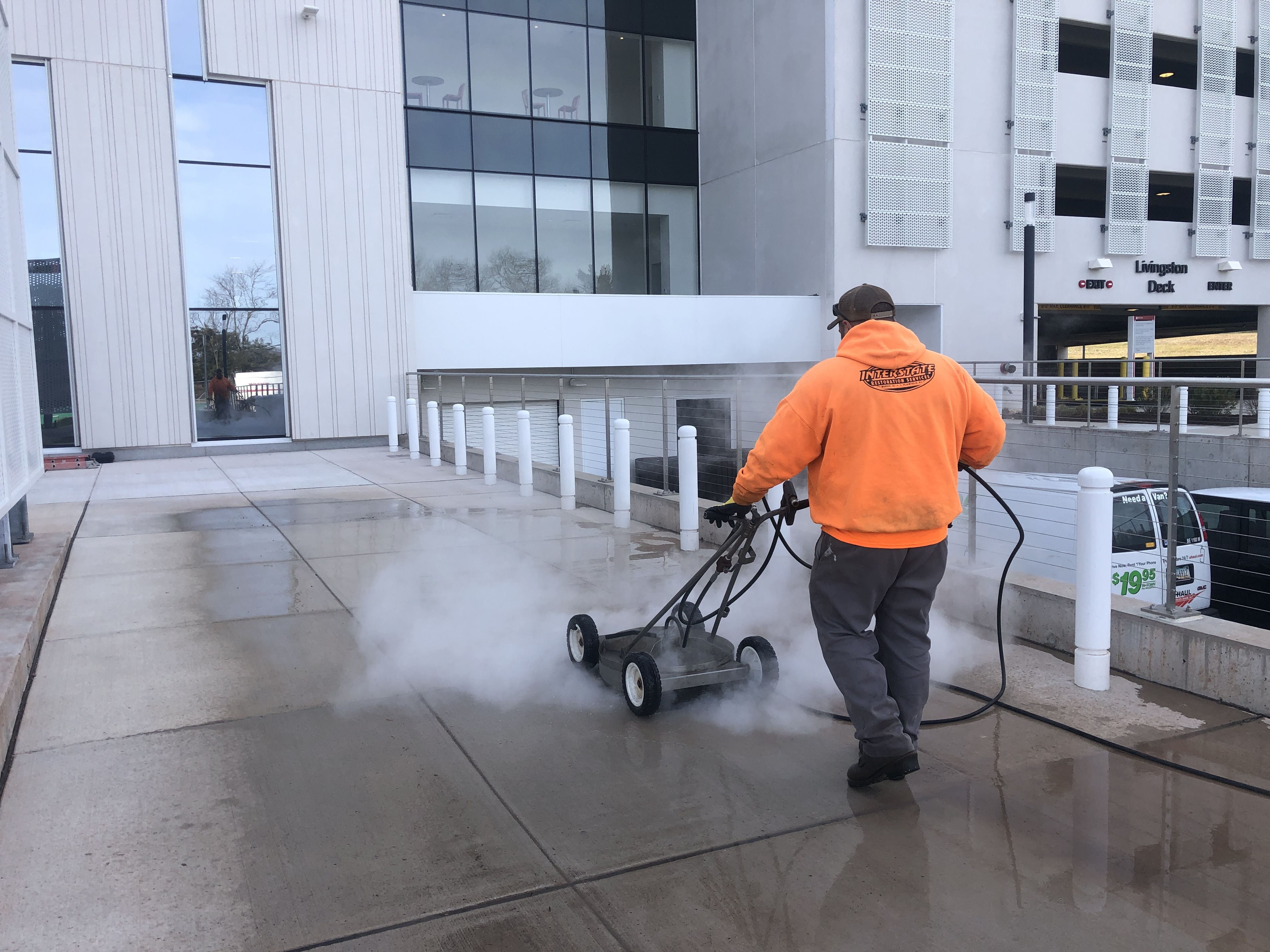 Commercial power washing technician cleaning exterior concrete