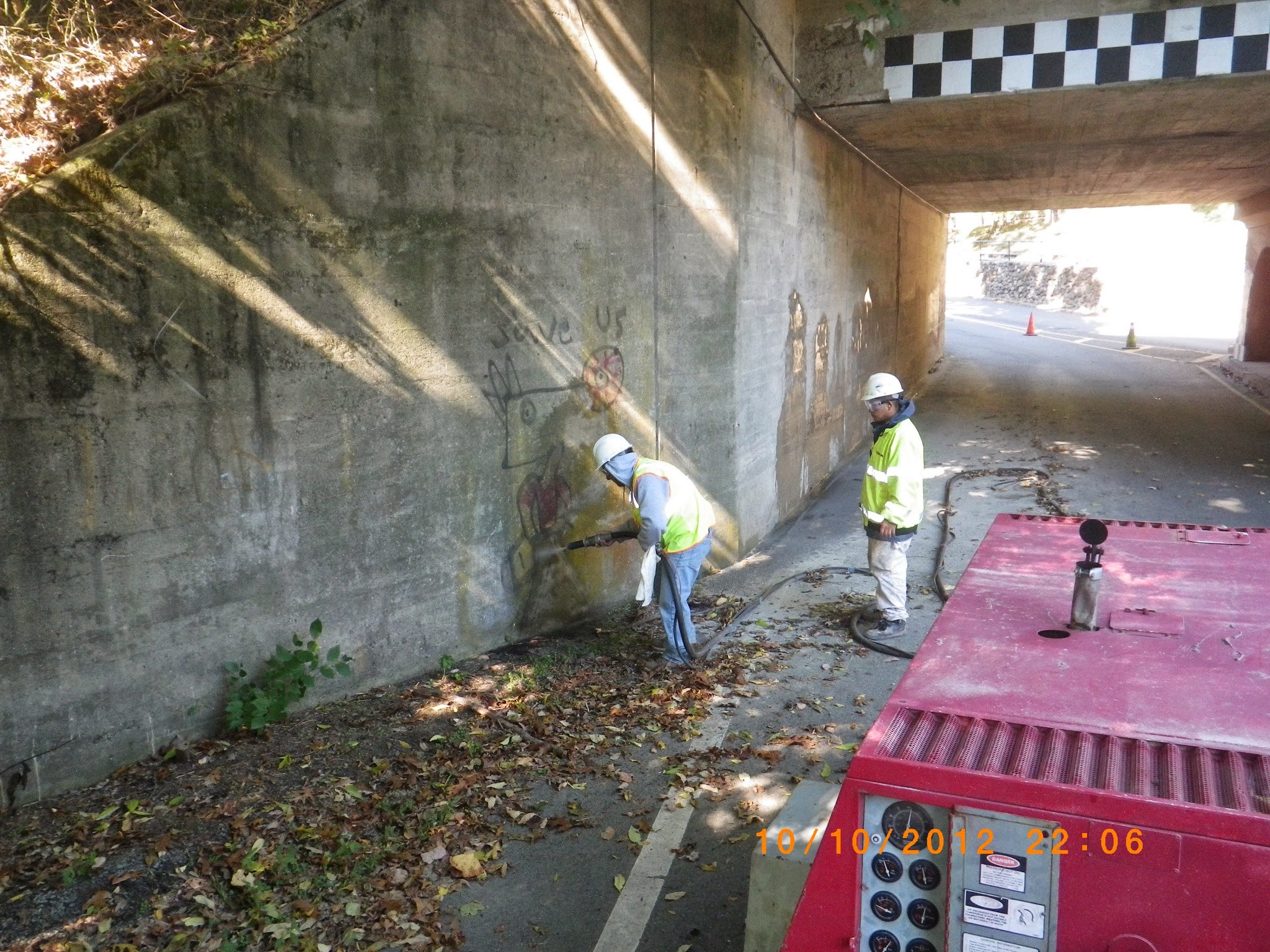 Crew cleaning coating under bridge or wall area